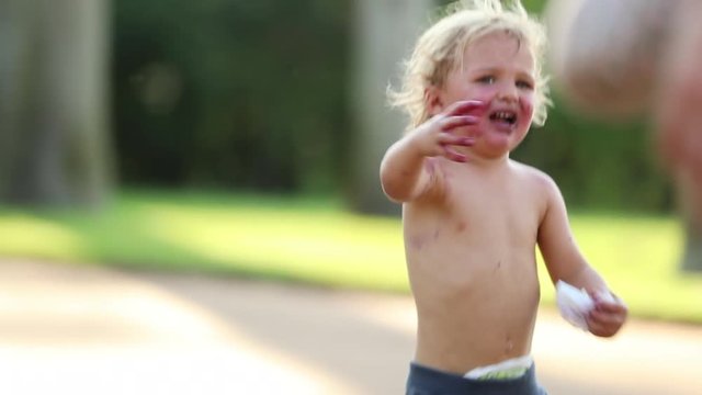 Candid moment of infant baby running towards mother. Toddler wanting the attention of his mom. Child looking tainted with red color after having eaten berries