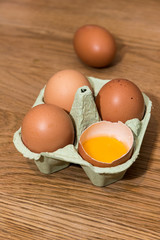 Close-up view of raw chicken eggs in egg box on  oak wooden background