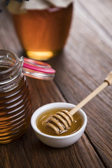 Honey in jar with honey dipper on wooden background 