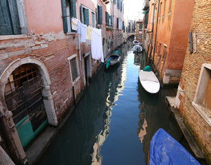 very narrow navigable canal in Venice in Italy with boats