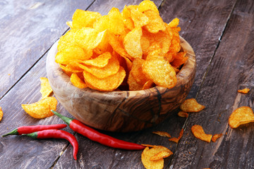 Crispy potato chips. Paprika chips on brown wooden background.