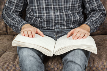 The blind man was reading a book written on Braille. Touch your finger on the braille code. A book with Braille text