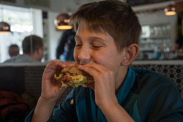 a boy eats staisfied a big burger