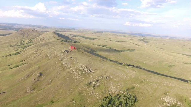 AERIAL: The paraglider flies over the rocky mountains against the backdrop of the countryside. Extreme weekend in wild places, flying people.
