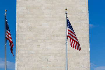 Two American Flags stand tall next to the looming Washington Monument