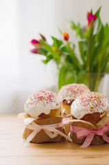 Traditional russian easter cake with  bright  decoration stand in group on the table. In background stand vase with tulips