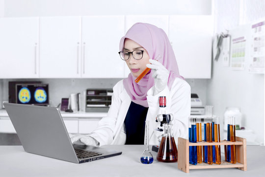 Scientist with test tube and laptop