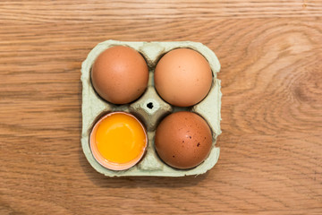 Close-up view of raw chicken eggs in egg box on  oak wooden background