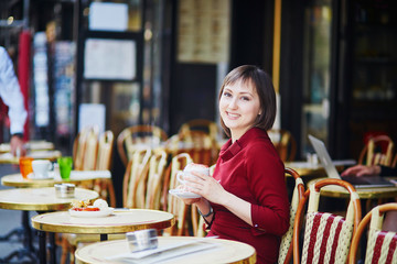 French woman drinking coffee in Parisian outdoor cafe