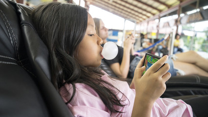 Girl with bubble gum playing game on phone