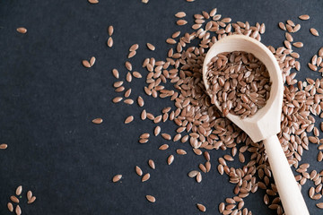 Flax seeds in spoons over dark background. Natural light. Selective focus. Close up on a black background. Top view, flat lay. copy space.
