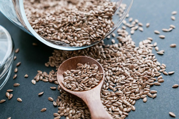 Flax seeds in spoons over dark background. Natural light. Selective focus. Close up on a black background. Top view, flat lay. copy space.