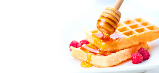 Belgian waffles with honey and berries closeup over white background