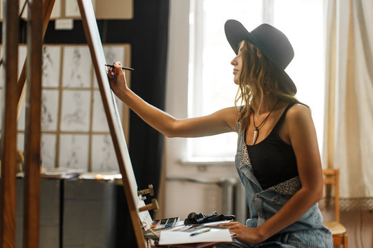 Female artist wears black hat draw picture indoor the studio