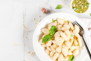 Italian food recipe, Healthy vegan dinner with potato gnocchi. With grated parmesan cheese, basil and pesto sauce. On white marble , copy space  top view
