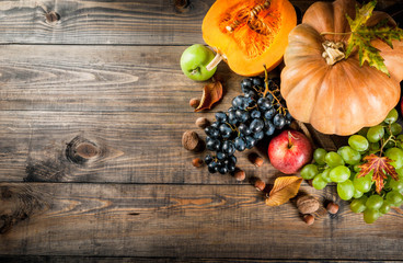 Autumn and thanksgiving harvest concept. Seasonal fall fruits and pumpkin on wooden table, copy space top view