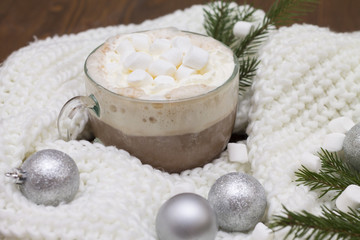 Fototapeta na wymiar delicious hot cocoa with marshmallows on the Christmas table Christmas balls, fir branches knitted scarf warmth and comfort