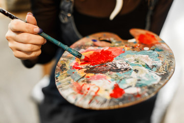 Caucasian artist putting red paint on his palette in the studio
