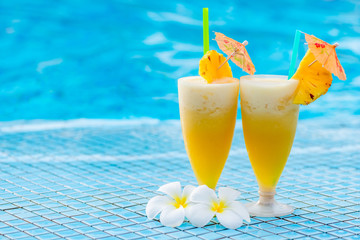 pineapple cocktail beautifully decorated with umbrellas and flowers on the edge of the pooll