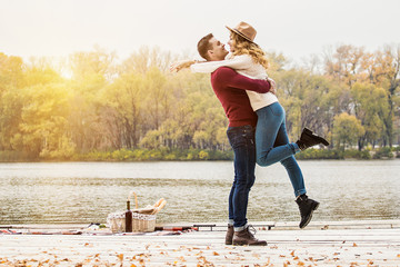 All I need is You. Horizontal shot of handsome man in casual clothing carrying his beautiful girlfriend while standing outdoors. Beautiful couple in love. Man embracing woman.