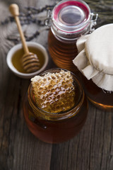 Honey in jar with honey dipper on wooden background 