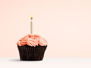 Pink cupcake with candle flame on pink background