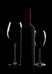 Glass of red wine with bottle with shape on black
