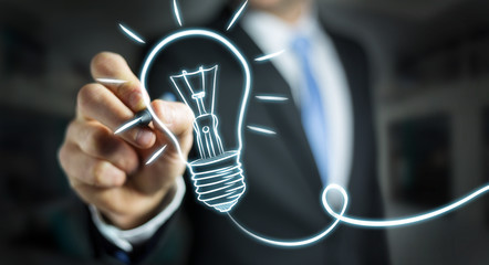 Businessman drawing a sketch lightbulb with a pen