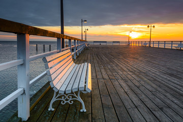 Bench on wooden pier in Jastarnia village. Hel Peninsula at sunset time. Poland. - obrazy, fototapety, plakaty