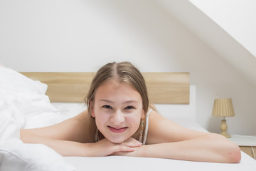 Fototapeta premium Happy smiling young teenage girl on a Saturday morning bed