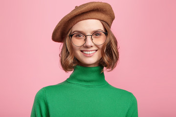 Charming delightful smiling woman dressed in retro clothes, has appealing appearance, demonstrates...