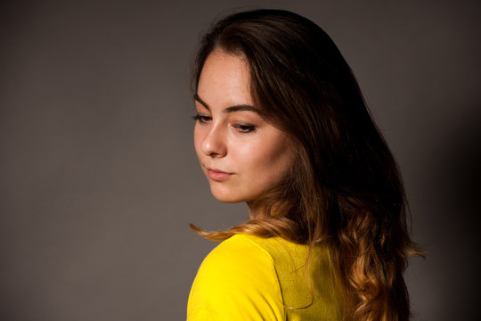 Portrait Of Beautiful Young Caucasian Woman In Yellow T Shirt Over Dark Gray Background