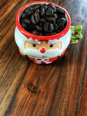 Merry Christmas,coffee beans in Cute Santa Claus Cup on the wooden table.