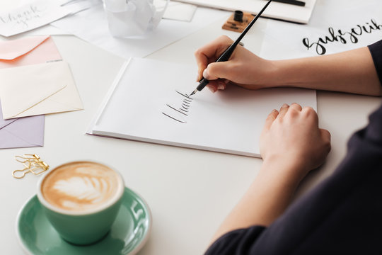 Beautiful photo of woman hands holding classic ink pen while writing notes on white desk