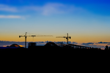Fototapeta na wymiar Skyline and silhouette of crane in building construction site on evening background