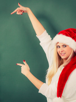 Woman in Santa hat pointing at green wall
