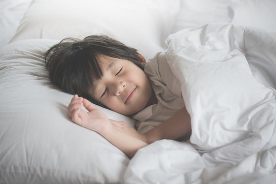 Cute Asian Child Sleeping On Bed