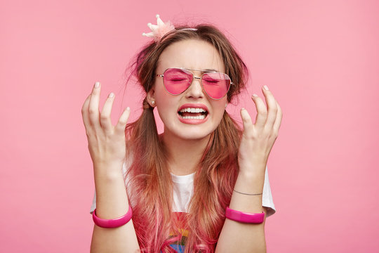 Desperate female wears pink glasses, gestures in puzzlement, being depressed as has no money for going shopping, cries in despair, doesn`t know how improve situation. People and frustration concept