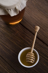 Honey dripping from a wooden honey dipper in a jar