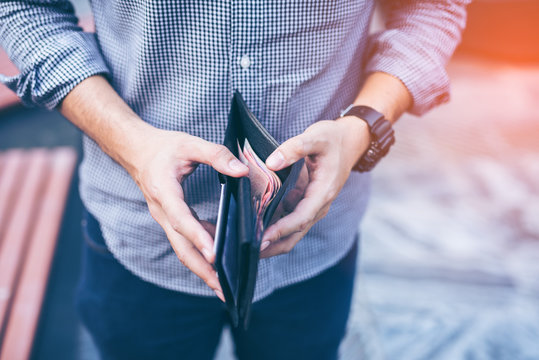 Man standing holding black wallet full of money