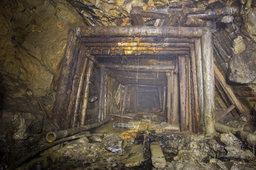 Underground abandoned gold ore mine shaft tunnel gallery passage with timbering