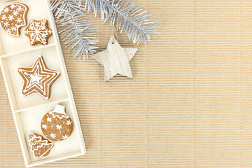 homemade gingerbread cookies and firtree branch with rustic wooden star on corrugated brown cardboard