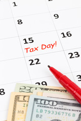 Tax day on calendar with red marker pen, and dollar banknote
