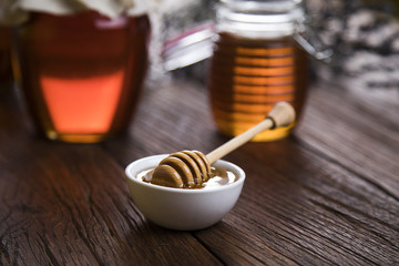 Honey in jar with honey dipper on wooden background 
