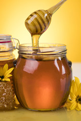 Honey dripping from a wooden honey dipper in a jar