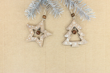 wooden rustic decorations hanging on silver christmas tree branches over brown paper background