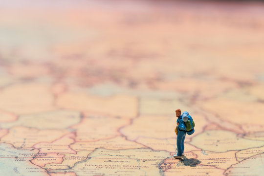 Miniature people: small figurine of lonely young traveler walking on big map