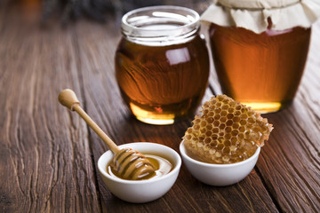 Honey in jar with honey dipper on wooden background 