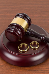 Wooden judge gavel and golden rings divorce concept