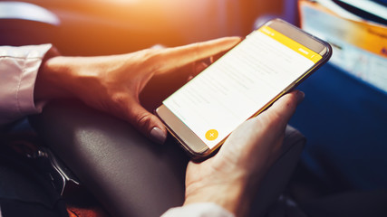 Female traveler using a smartphone surfing the internet while sitting in an aircraft